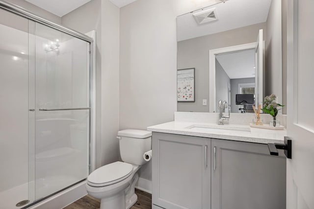 bathroom featuring toilet, a shower stall, wood finished floors, and vanity