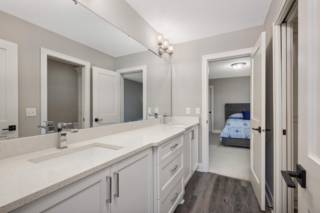 full bath featuring double vanity, wood finished floors, connected bathroom, and baseboards