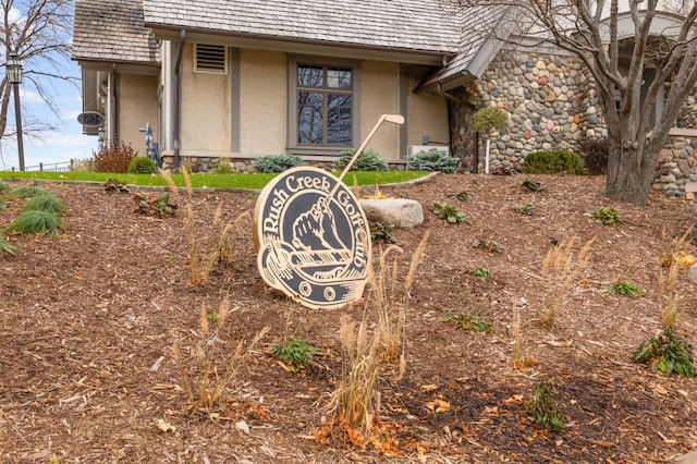 exterior view of stucco siding, a downspout, stone siding, and gutters