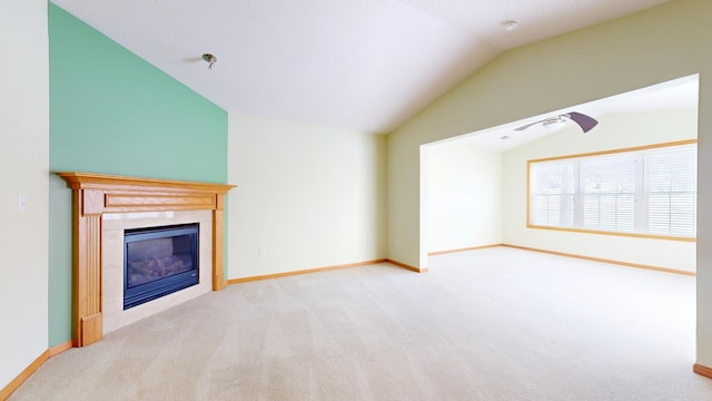 unfurnished living room featuring lofted ceiling, a glass covered fireplace, light carpet, and baseboards