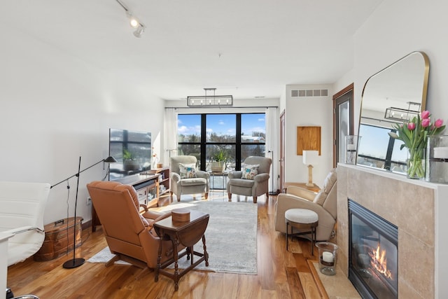 living room with visible vents, a fireplace with flush hearth, wood finished floors, and track lighting