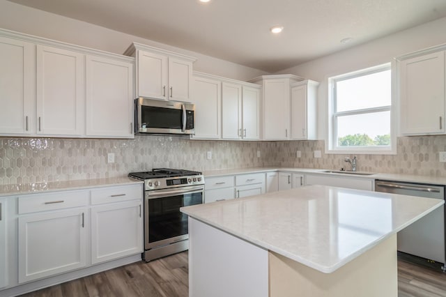 kitchen featuring sink, a center island, light wood-type flooring, appliances with stainless steel finishes, and white cabinets