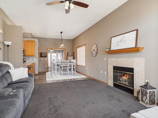 living room featuring a tile fireplace, ceiling fan, and dark carpet