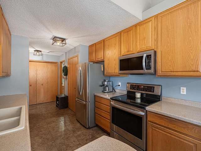 kitchen featuring appliances with stainless steel finishes, sink, and a textured ceiling