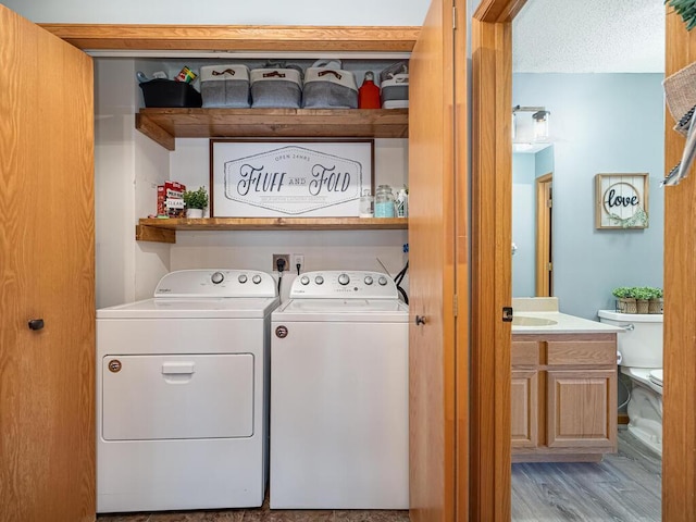 clothes washing area featuring separate washer and dryer, a textured ceiling, and light wood-type flooring