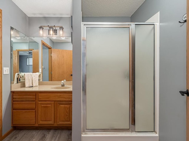 bathroom with vanity, wood-type flooring, a textured ceiling, and walk in shower