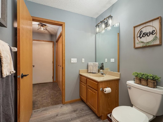 bathroom with hardwood / wood-style flooring, vanity, toilet, and a textured ceiling