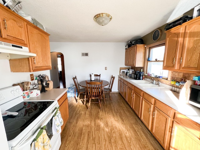 kitchen with sink, light wood-type flooring, a textured ceiling, and white range with electric cooktop