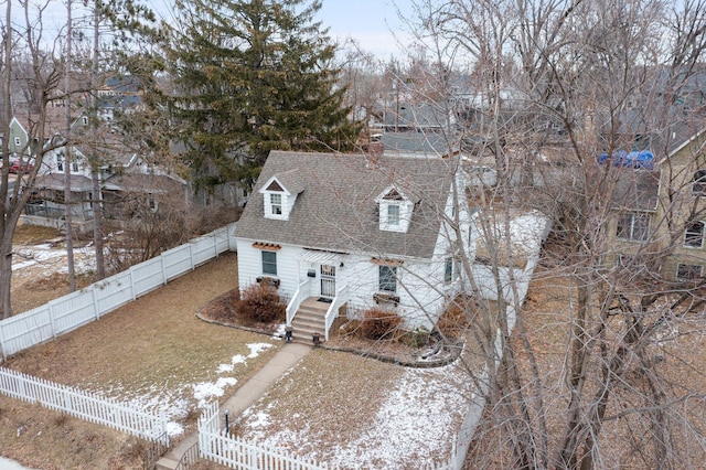 cape cod home with a fenced backyard and a shingled roof