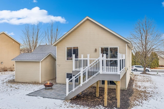 snow covered rear of property featuring an outdoor fire pit and a patio area