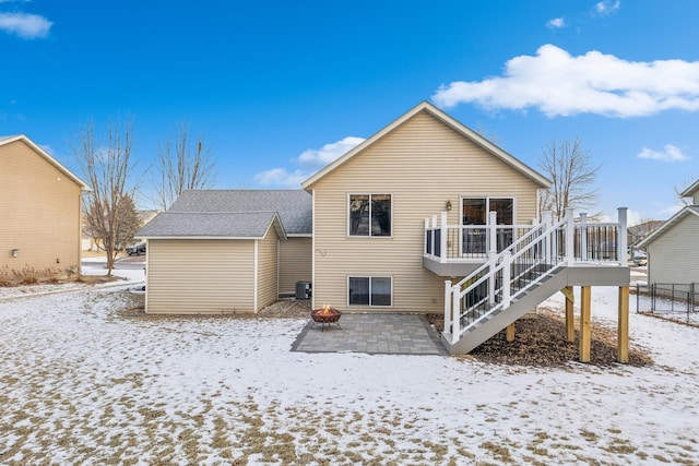 snow covered property featuring a wooden deck, cooling unit, and a fire pit