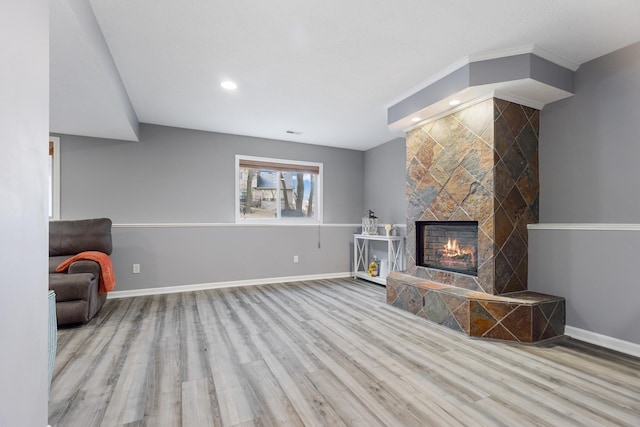 unfurnished living room featuring a tiled fireplace and light wood-type flooring