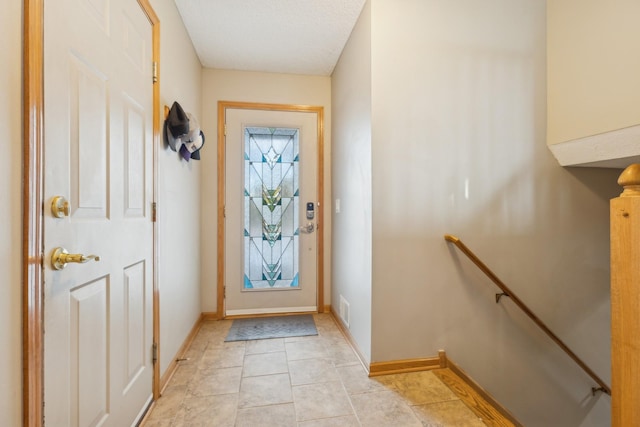 doorway featuring light tile patterned flooring and a textured ceiling