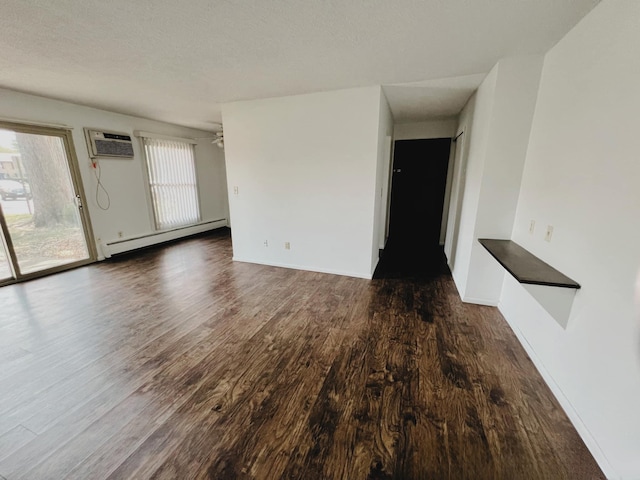 empty room with a textured ceiling, dark wood-type flooring, a wall mounted AC, and baseboard heating