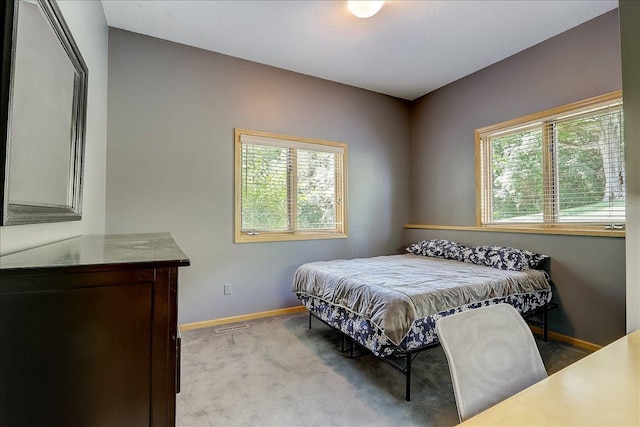 bedroom featuring light colored carpet and multiple windows