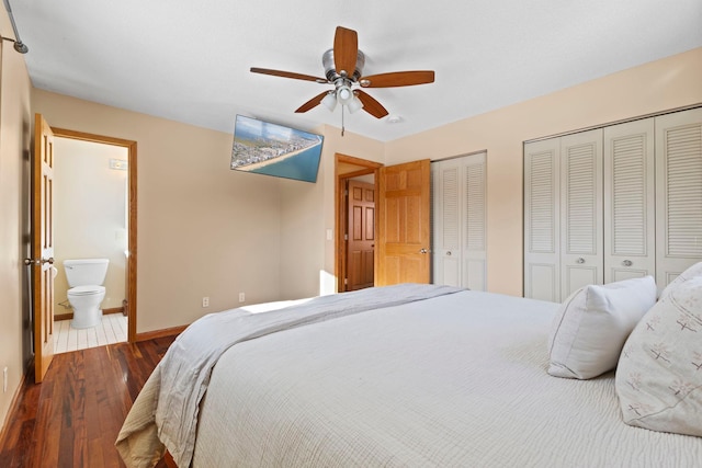 bedroom featuring connected bathroom, dark wood-type flooring, two closets, and ceiling fan