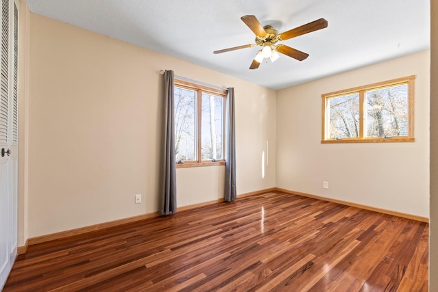 unfurnished room featuring ceiling fan, a healthy amount of sunlight, and dark hardwood / wood-style flooring