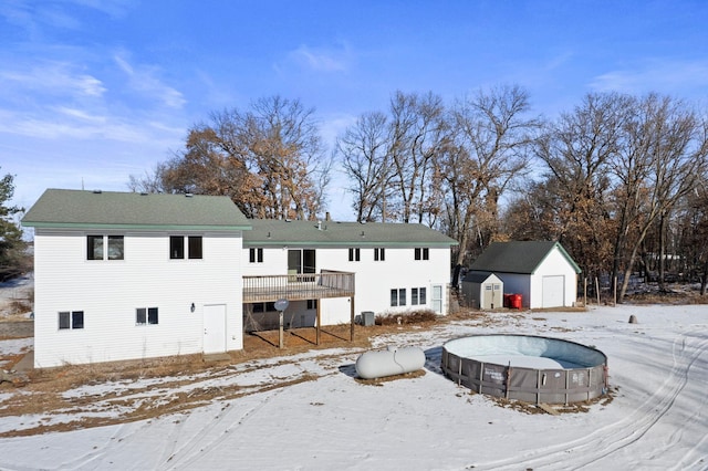 snow covered rear of property featuring a wooden deck, central AC, and a shed