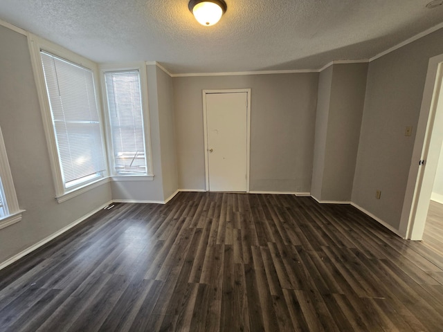 empty room with dark wood-type flooring, ornamental molding, and a textured ceiling