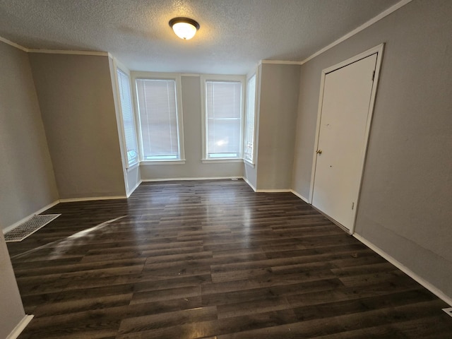 spare room featuring ornamental molding, dark hardwood / wood-style floors, and a textured ceiling