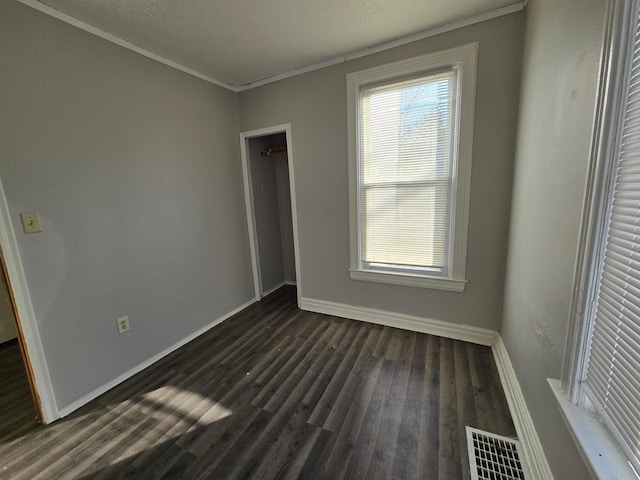 unfurnished bedroom featuring crown molding, dark hardwood / wood-style flooring, and a closet