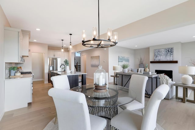 dining area with light wood-style flooring, a chandelier, recessed lighting, a fireplace, and baseboards
