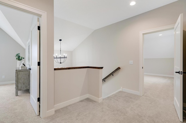 hallway featuring an upstairs landing, lofted ceiling, light colored carpet, a chandelier, and baseboards