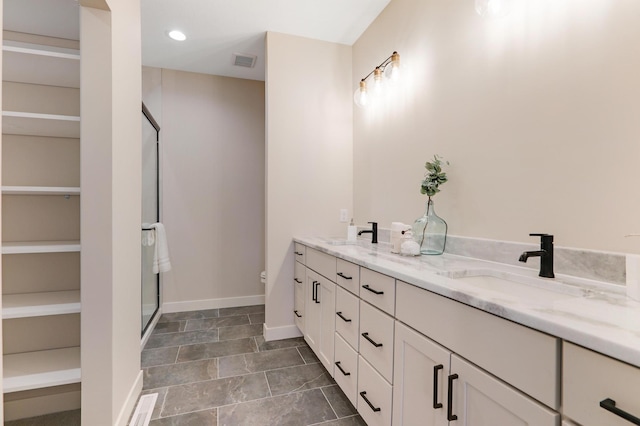 bathroom with a stall shower, double vanity, baseboards, toilet, and a spacious closet
