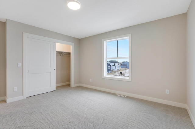 unfurnished bedroom featuring light colored carpet, baseboards, and a closet