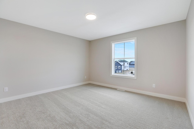 empty room featuring light carpet and baseboards