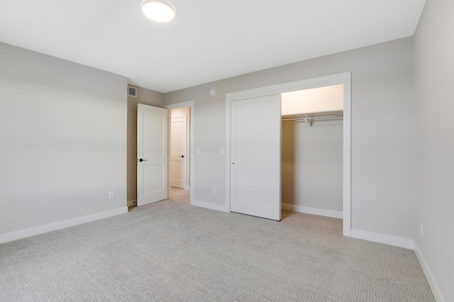unfurnished bedroom featuring light carpet, baseboards, and a closet