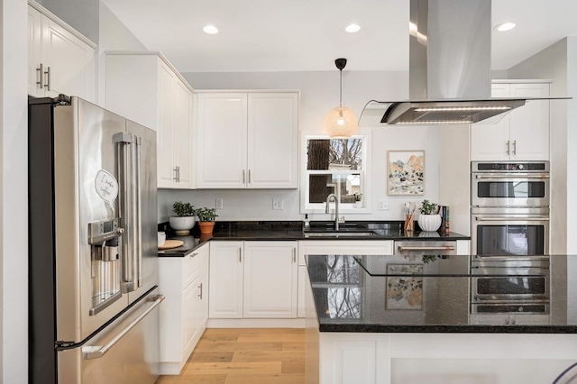 kitchen featuring appliances with stainless steel finishes, decorative light fixtures, sink, white cabinets, and island exhaust hood