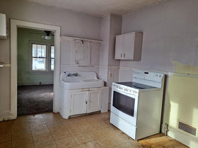 kitchen with white cabinets, sink, and electric range