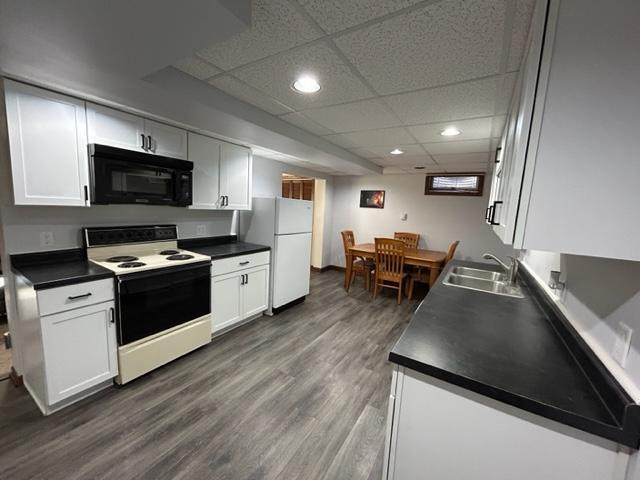 kitchen with white appliances, dark hardwood / wood-style flooring, sink, and white cabinets