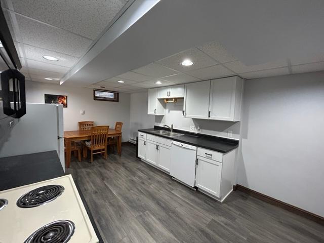 kitchen with dark hardwood / wood-style floors, white cabinetry, sink, a drop ceiling, and white appliances