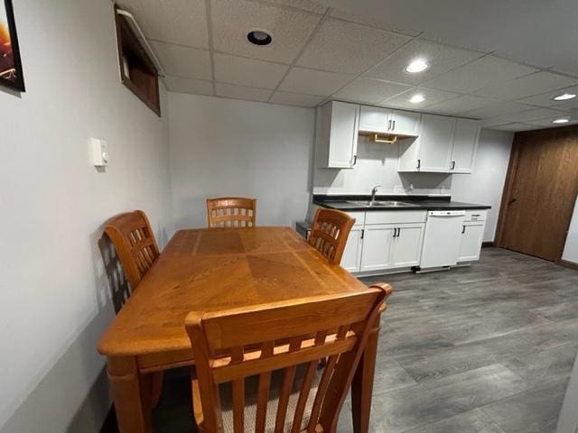 dining space featuring a paneled ceiling, wood-type flooring, and sink