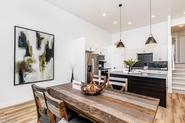 dining area with a high ceiling and light wood-type flooring