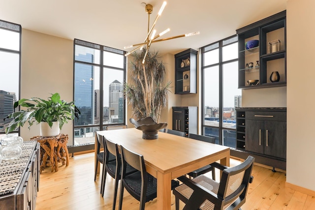 dining space with a notable chandelier, expansive windows, and light wood-type flooring