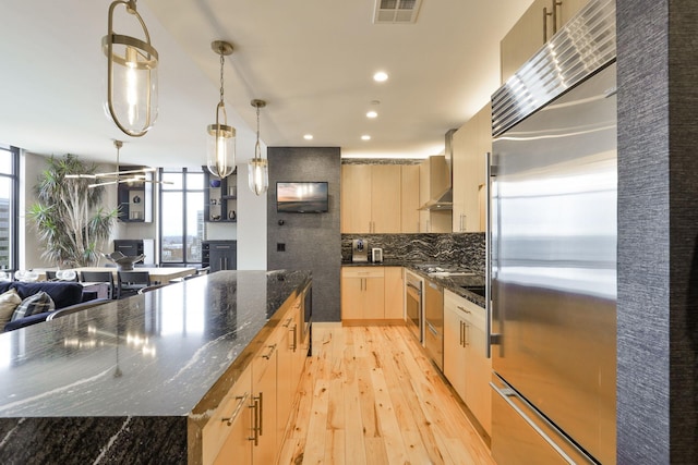 kitchen with pendant lighting, light hardwood / wood-style flooring, light brown cabinetry, high end refrigerator, and dark stone counters