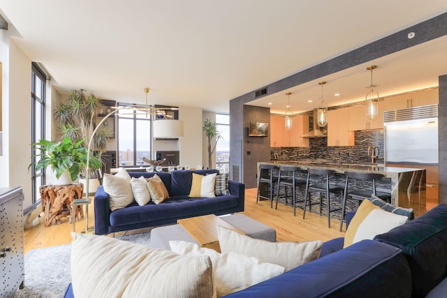 living room featuring expansive windows, a healthy amount of sunlight, sink, and light hardwood / wood-style flooring