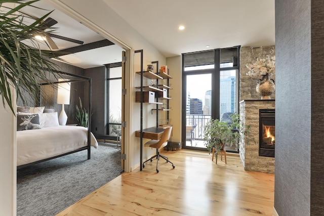 bedroom featuring expansive windows, hardwood / wood-style flooring, access to outside, and a fireplace