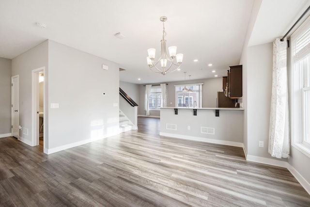 kitchen with pendant lighting, stainless steel refrigerator, a breakfast bar area, hardwood / wood-style flooring, and kitchen peninsula