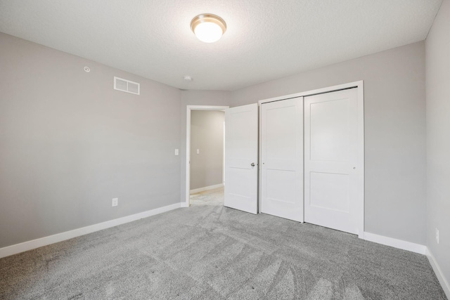 unfurnished bedroom featuring a closet, a textured ceiling, and carpet flooring