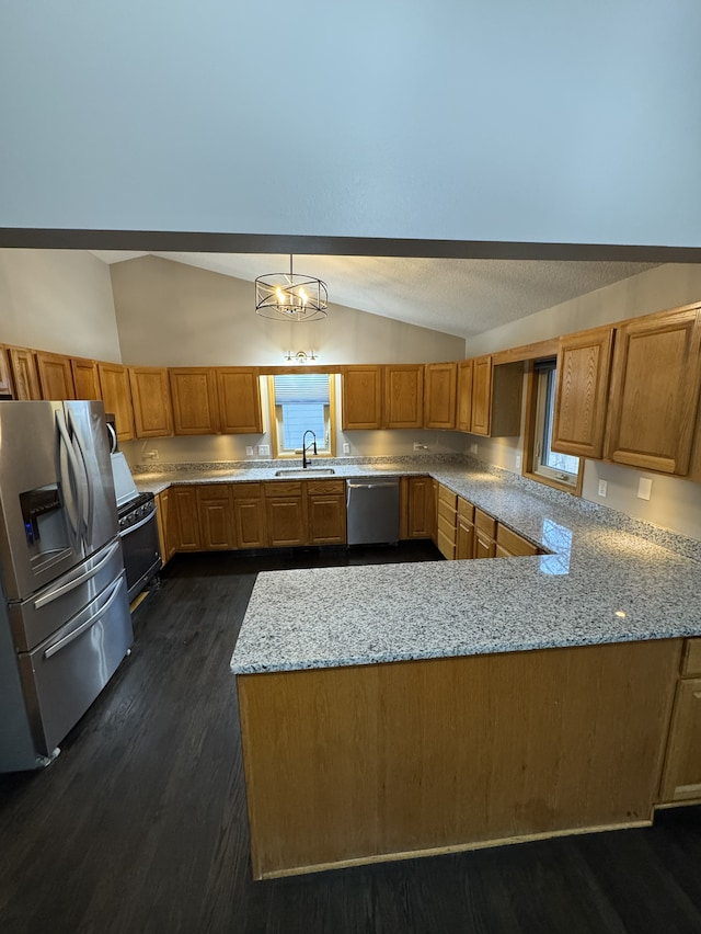 kitchen with sink, appliances with stainless steel finishes, hanging light fixtures, vaulted ceiling, and kitchen peninsula