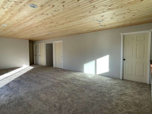 carpeted spare room featuring wooden ceiling