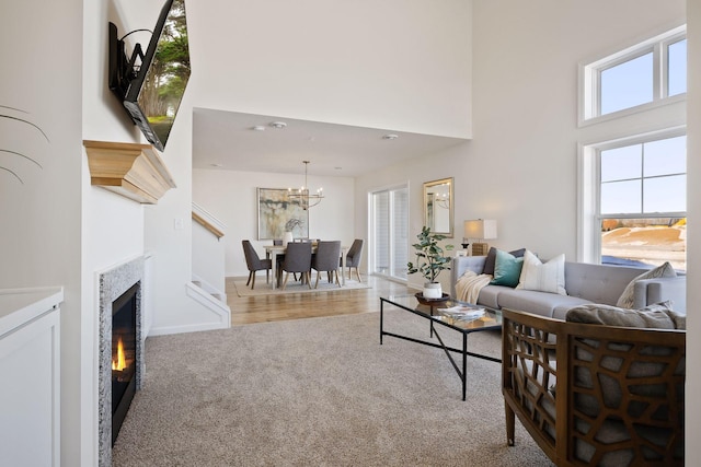 living room with a notable chandelier, light colored carpet, and a high ceiling