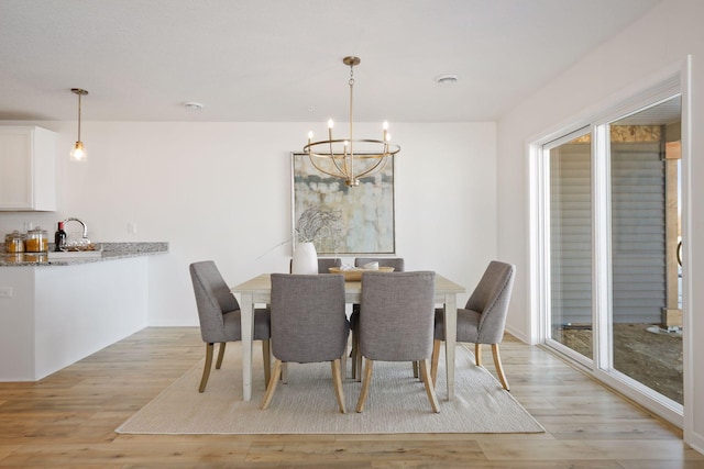 dining room with an inviting chandelier, a wealth of natural light, and light wood-type flooring