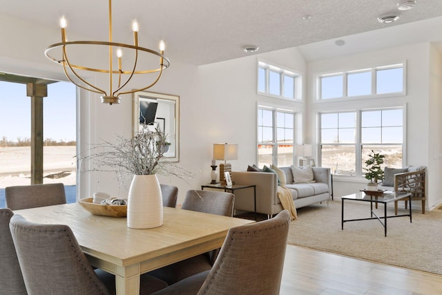 dining space featuring an inviting chandelier, light hardwood / wood-style flooring, and a textured ceiling