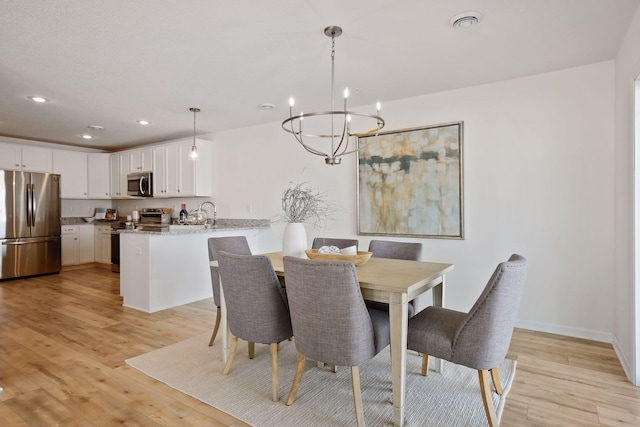 dining space with an inviting chandelier and light hardwood / wood-style floors