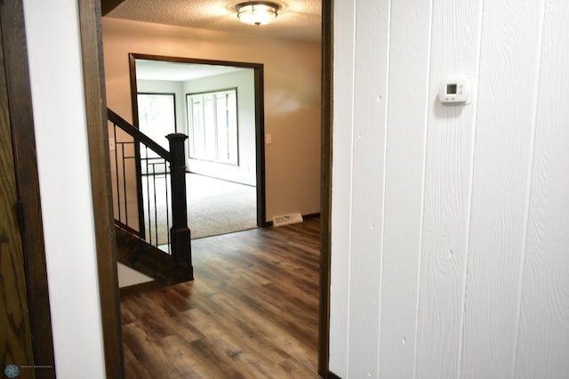 corridor with dark hardwood / wood-style flooring and a textured ceiling